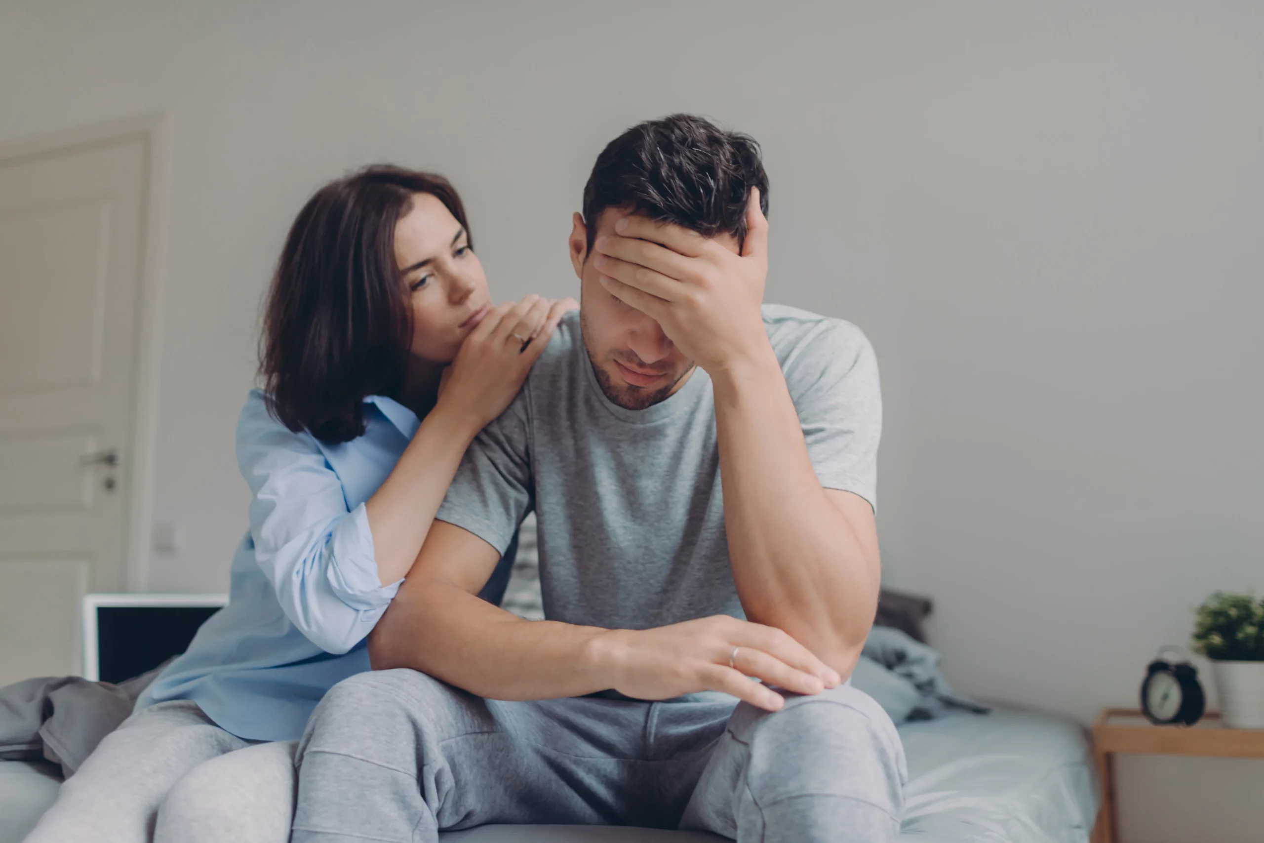 a woman consoling her boyfriend in a bedroom