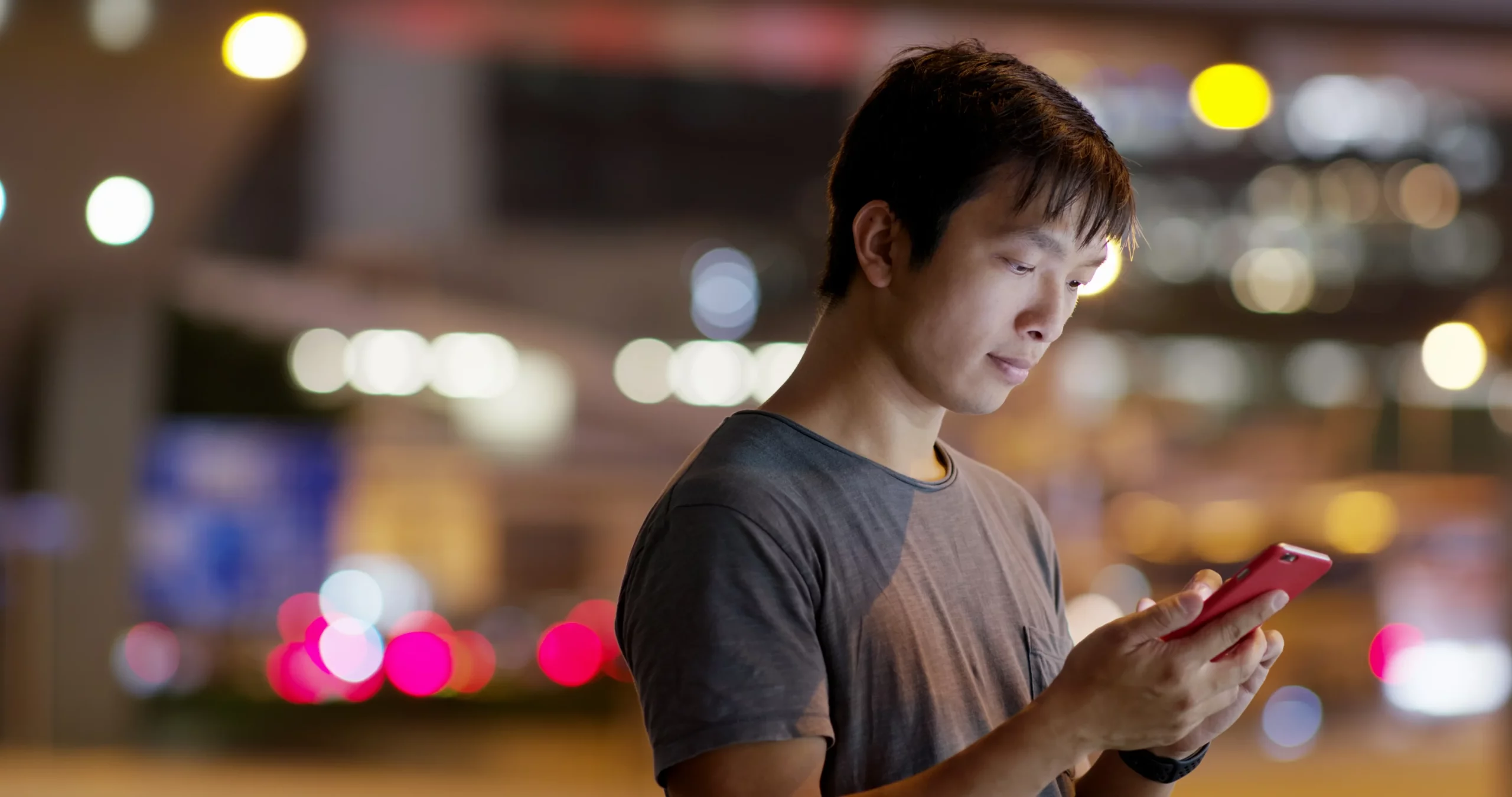 man looking at his phone in the middle of the street at night